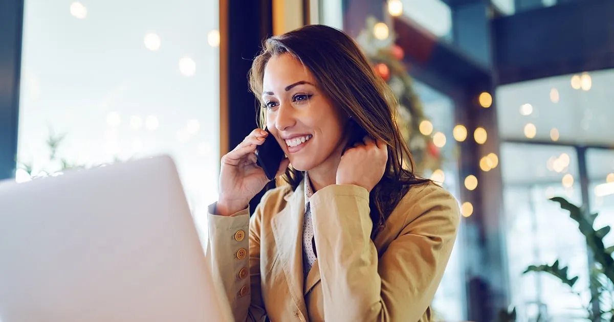 Woman talking on the phone while looking at a laptop